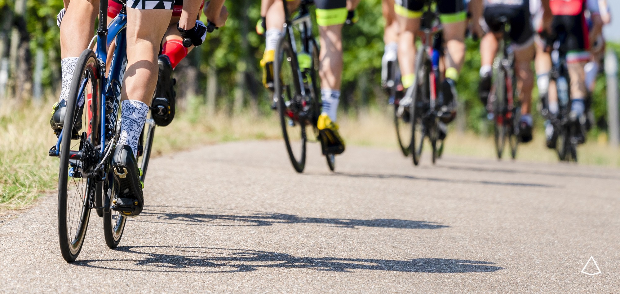 Serie di ciclisti in una competizione inquadrati posteriormente dal basso.