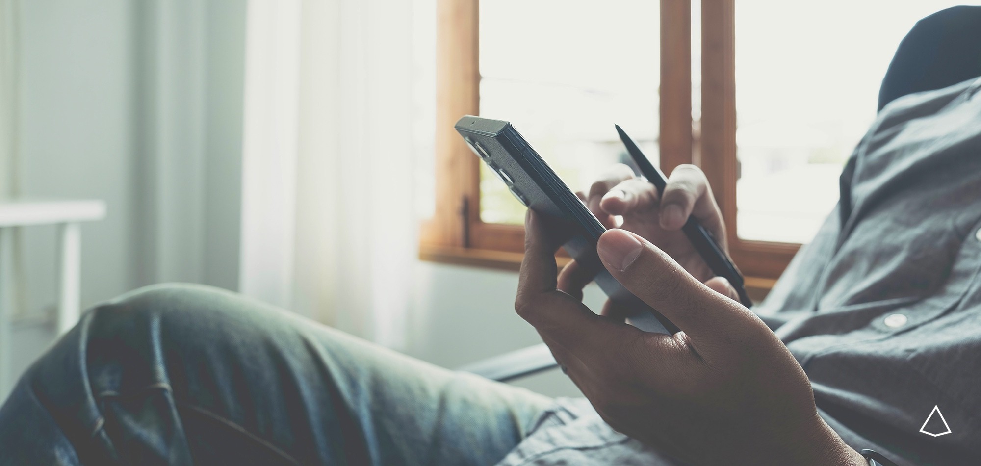 Dettaglio di un ragazzo seduto intento a cercare informazioni sullo smartphone.